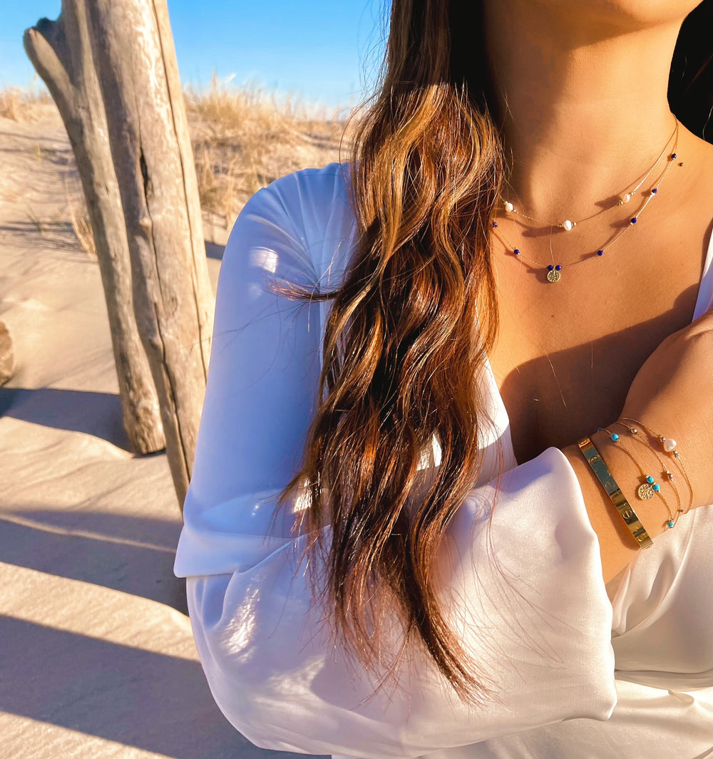 Olivia Le model at the beach wearing the Journey Pearl Bracelet stack with the Journey collection bracelets and necklaces